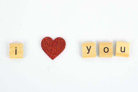 I love you spelled out with wooden blocks and red heart on white backgroundの写真素材