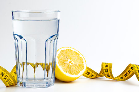 A glass of water with lemon and measuring tape on white background.の写真素材