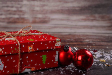 Christmas gift box with red ball on wooden background. Close up.