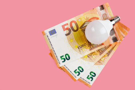 Bulb on 50 euro banknote isolated on pink background. Energy saving concept