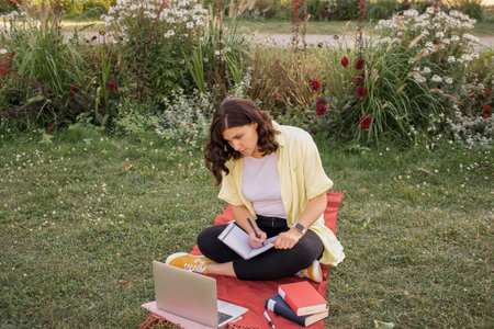 Young woman freelancer working in park with laptop. High quality photo
