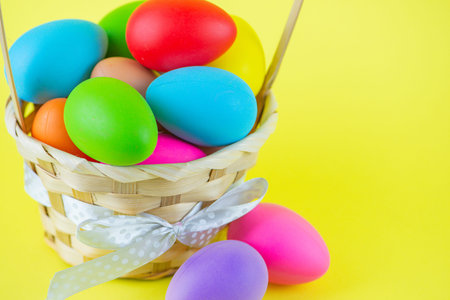 Colored Easter Eggs in Basket on Yellow Background, Happy Easter