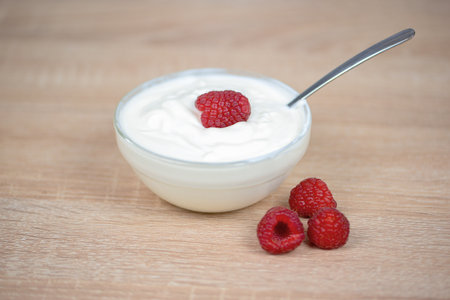 A deliciously creamy yogurt bowl adorned with a fresh raspberry, making it perfect for a healthy snack choiceの写真素材