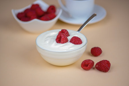 white yogurt on the table with raspberries close-up, healthy breakfast in the kitchenの写真素材