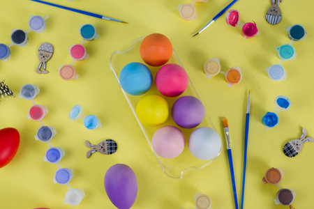 Colored Easter Eggs with Brushes and Paints on a Yellow Background with Space for Text.