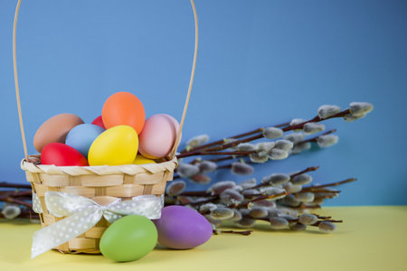 Easter colored eggs in basket on blue background with willow. High quality photoの写真素材