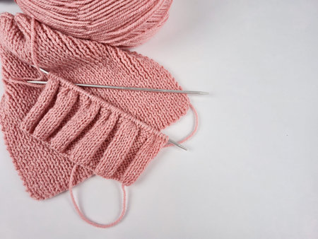 Pink knitting in progress. knitting needles and neat loops creating a textured pattern. a ball of...