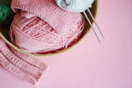 Different yarns, knitting needles and pattern sample in bowl, closeup. High quality photo