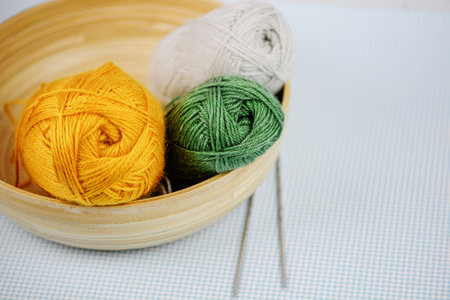 Three vibrant yarn balls rest in a decorative bowl, perfect for endless crafting and knitting...