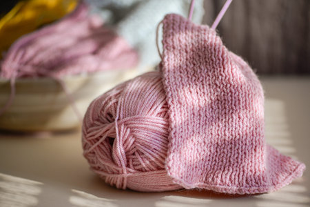 A cozy pink yarn ball accompanied by an unfinished knitting project that showcases the essence of...