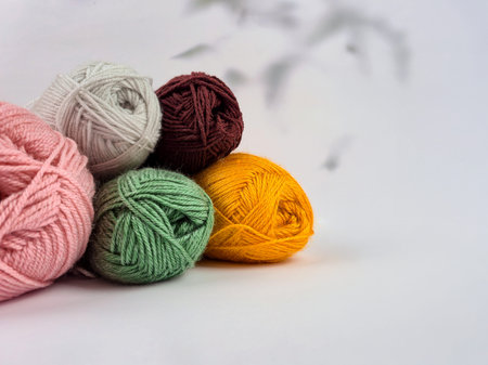 Colorful skeins of yarn laid out on a white background. The texture of the soft fibers is clearly...