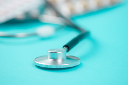 A detailed view of a polished stethoscope elegantly placed on a vibrant turquoise surface, symbolizing healthcareの写真素材