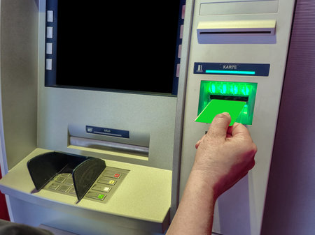A women hand inserts a blue credit card into an ATM card reader. Women hand with manicure and a banking card. High quality photoの写真素材