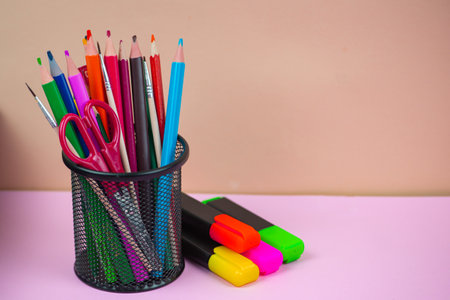 A vibrant and visually appealing collection of colorful pens, markers, and scissors organized neatly in a black holderの写真素材
