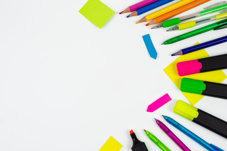 A vibrant arrangement of pens, colorful markers, and sticky notes beautifully placed on a clean white surfaceの写真素材