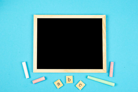 A colorful chalkboard with bright chalk pieces and cheerful alphabet blocks on a lively blue backgroundの写真素材