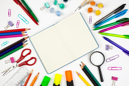 Colorful stationery items are beautifully arranged around a blank notebook on a clean white backgroundの写真素材