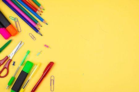 A delightful array of vibrant stationery items artfully arranged on a lively and bright yellow...