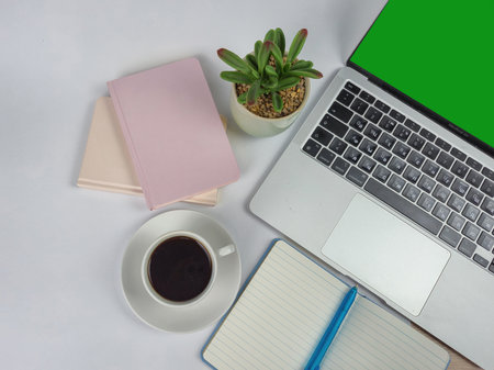 A stylish workspace featuring a laptop, coffee cup, notebooks, and a bright plant to enhance the atmosphereの写真素材