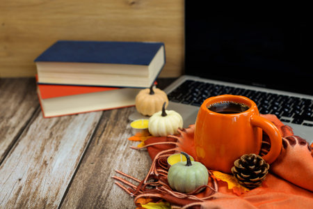 A cozy warm autumn scene featuring stacked books, steaming coffee, and beautifully arranged...