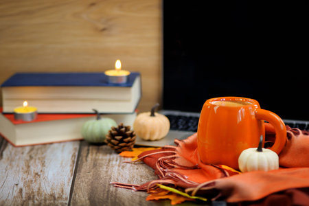hot cup of coffee with autumn decor, books and laptop, thanksgiving. High quality photo