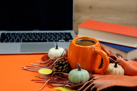 hot cup of coffee with autumn decor, books and laptop, thanksgiving. High quality photo