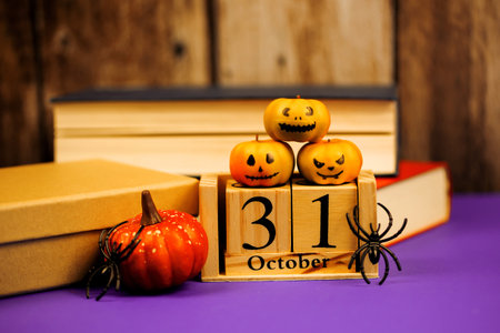 Wooden calendar with pumpkins and spider on a background of books.の写真素材