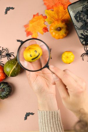 Enjoy festive autumn decorations with mini pumpkins and a charming magnifying glass for Halloween funの写真素材
