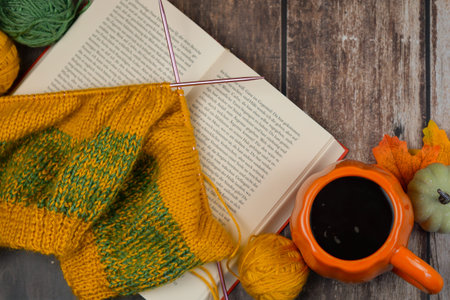 A serene scene with knitting supplies, an interesting book, and a warm beverage, ideal for cozy...