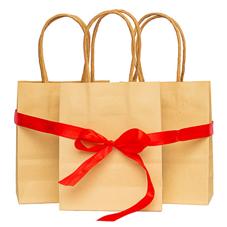 Three brown paper bags tied with a red ribbon on a white background. High quality photoの写真素材