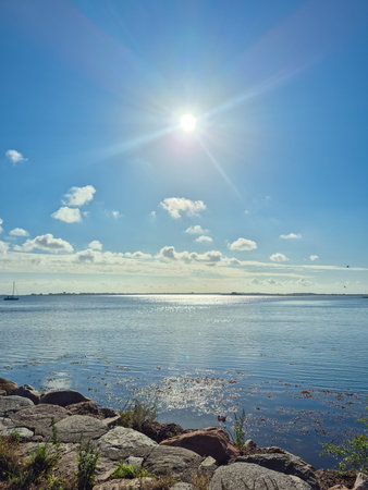 A beautifully tranquil lakeside scene depicts stunning clear blue skies, sparkling water, and...
