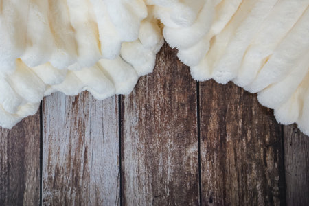 Warm beige plush plaid close-up on wooden background. High quality photoの写真素材