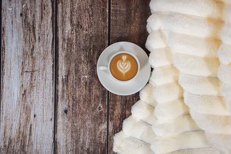 Hot coffee on a wooden background with a soft fluffy blanket and space for text. High quality photoの写真素材