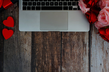 laptop with hearts and roses on a wooden background with space for text, happy valentines day