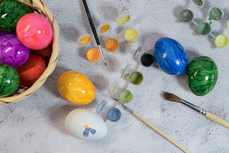 Close-up view of f painting an Easter egg with colorful paints.