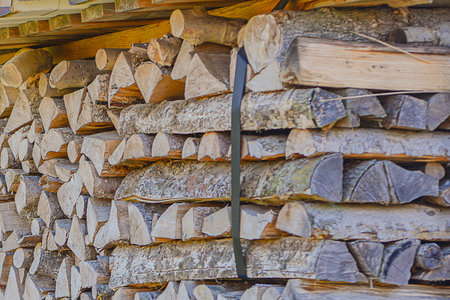 Stacked Oak Logs In Shed, Weathered Split Firewood Bound By Strap, Layered Rows Under Wooden Roof...