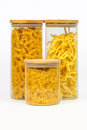 Variety of italian pasta in glass jars uncooked on white kitchen background, closeup, zero waste, eco friendly, balanced diet food, healthy clean eating conceptの写真素材