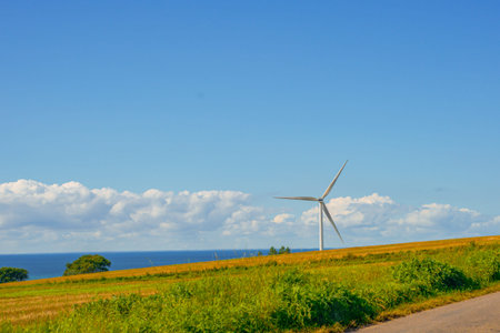 Gentle Breeze At Remote Coastal Station. Engineered Wind Generator Alongside Tranquil Shoreline Horizon Sceneryの写真素材
