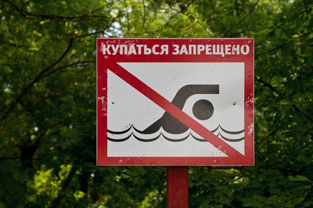 Red sign prohibiting swimming in the lake in the woodsの写真素材