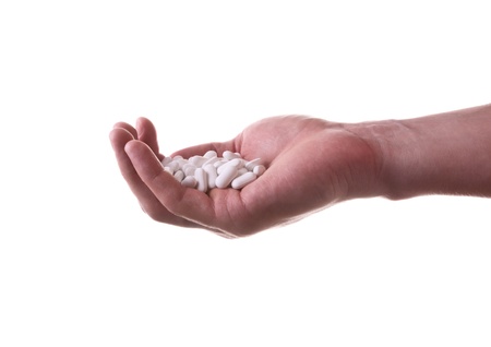 A hand with a bunch of pills on a white backgroundの写真素材