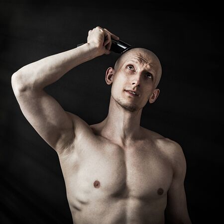 A young man shaves his head with an electric razorの写真素材