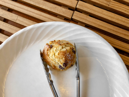 Bun with raisins on a white plant on a wooden table.の写真素材