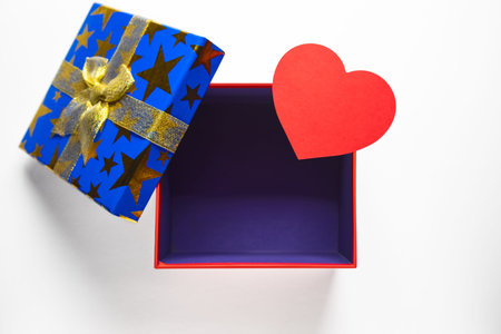 Gift or present empty box with golden ribbon and paper heart on white background top view.