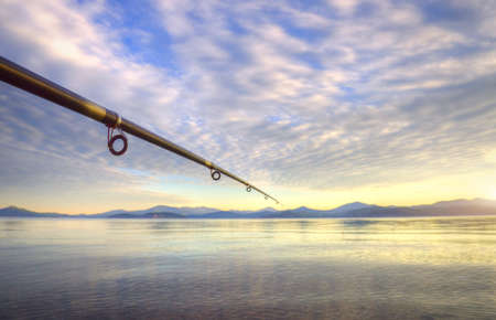 Spinning - fishing rod on the summer lake at sunsetの写真素材