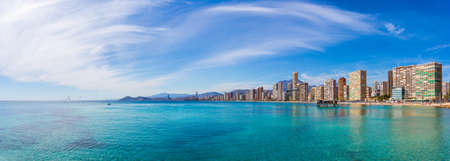 Panorama of the coast of the city with beautiful sky with clouds and clear blue water on the background of urban buildings and mountains.の写真素材