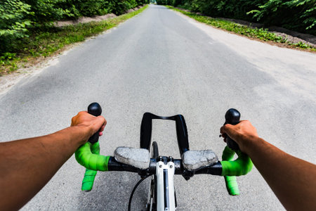 Riding on flat road asphalting in the forest. Hands on the steering wheel bicycle. Eye view from...