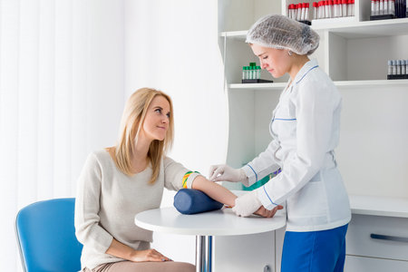 Preparation for blood test with beautiful young blond woman by female doctor in white coat medical...