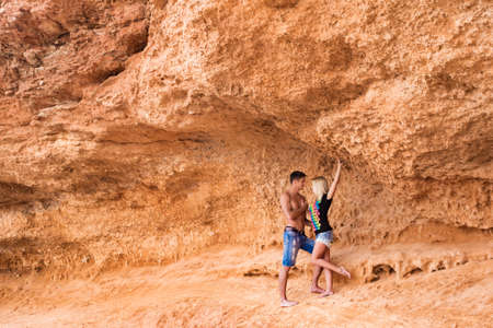 beautiful couple looking at each other before kiss on orange Coastal rocks backgroundの写真素材