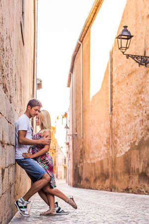 Beautiful couple hugging in narrow spainish street in shadow from big wallの写真素材