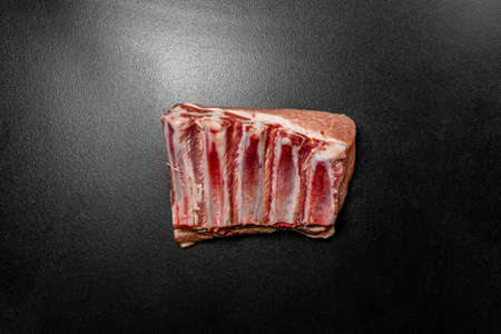 Raw pork ribs on black background. Fresh pork ribs or loin bone of pig. Piece of red raw meat on a black backgroundの写真素材